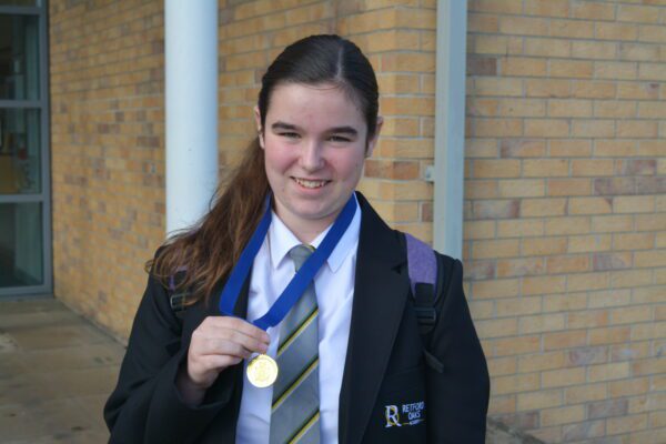 Year 9 student Chloe smiles whilst holding a gold medal