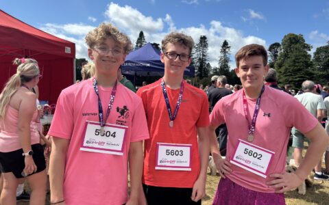 Three boys wearing pink t-shirts after running the race for life